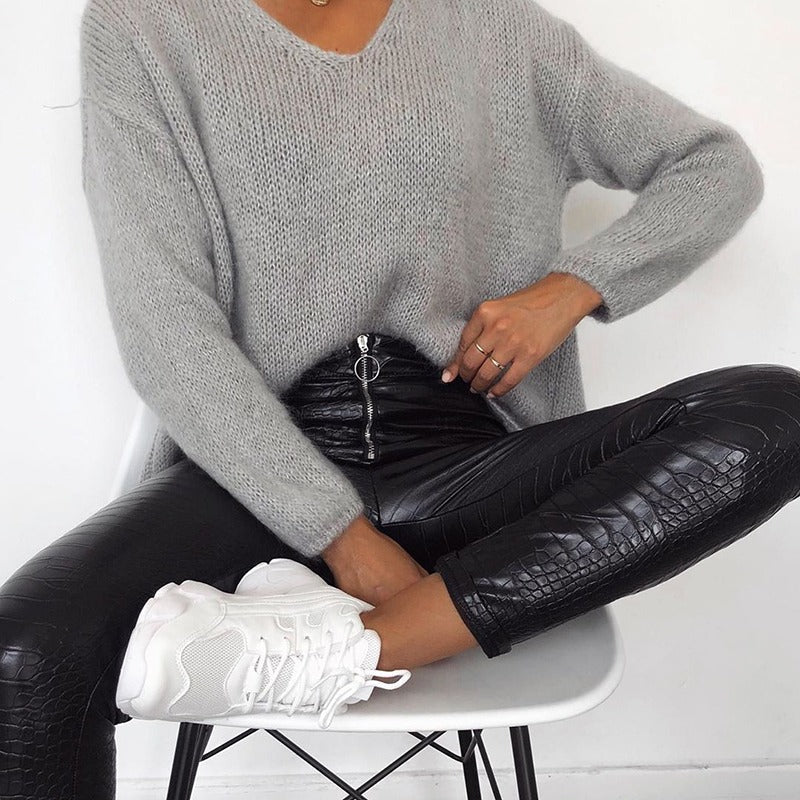 Elegant high waist faux leather pants with zip detail, paired with a cozy gray sweater and sporty white sneakers.