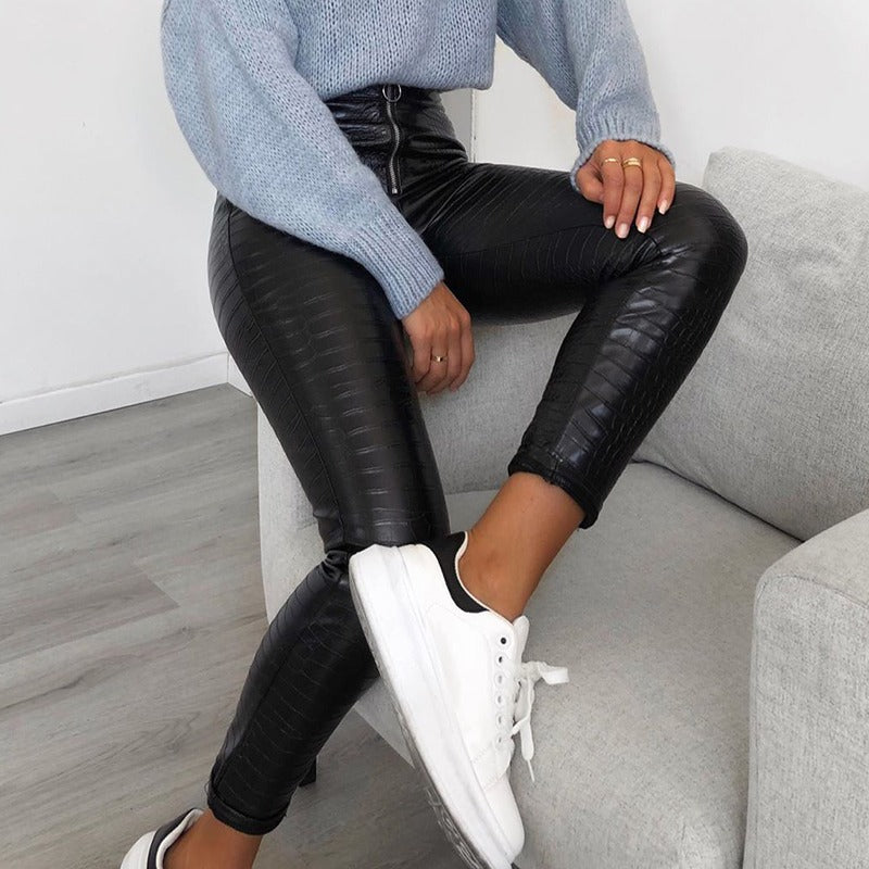Elegant high waist faux leather skinny pants in snake print, styled with a cozy sweater and sneakers.