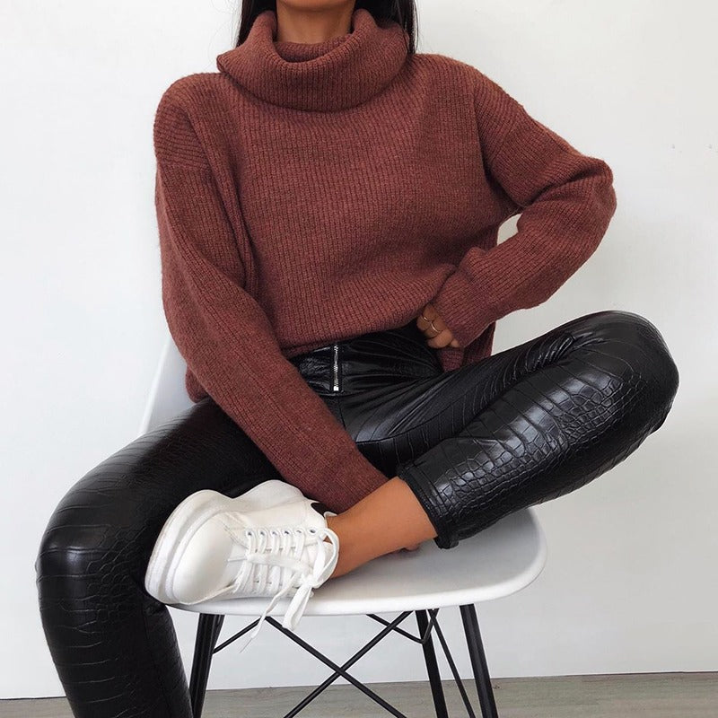 Casual outfit featuring a model in a cozy rust sweater and sleek black faux leather pants, styled with white sneakers.