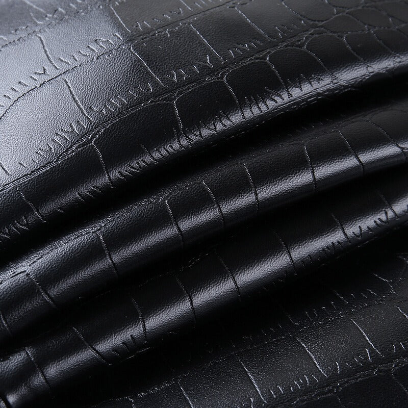 Close-up of elegant black faux leather fabric with snake print, perfect for stylish rock-inspired outfits.