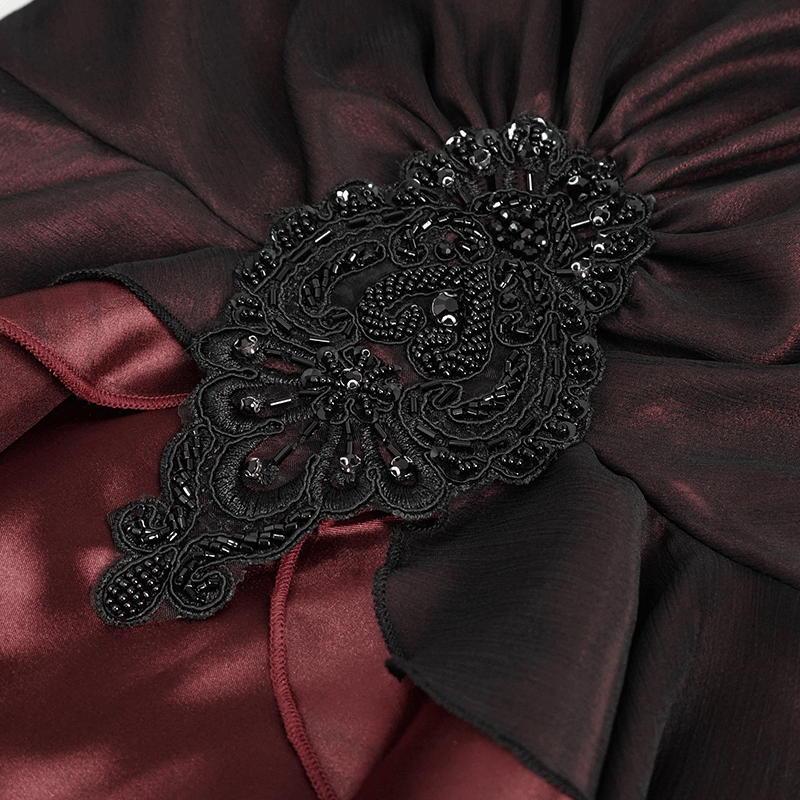 Close-up of elegant black lace and appliquéd detail on wine red gothic dress fabric, showcasing intricate design.