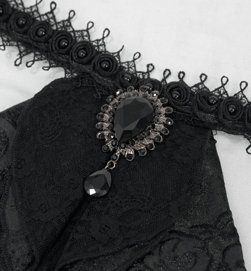 Close-up of elegant black patterned satin jabot tie with intricate brooch detail for gothic style.