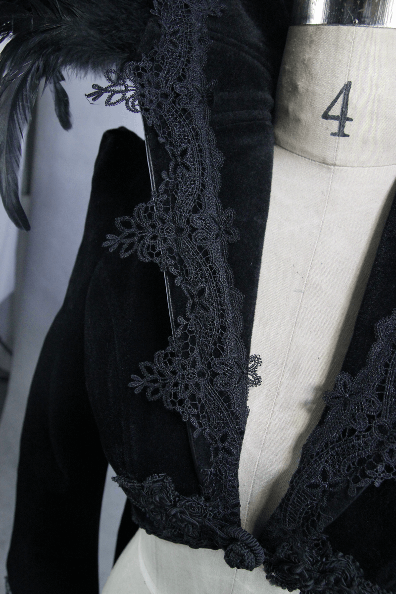 Close-up of elegant black velvet coat with feather collar and intricate gothic embroidery trim.
