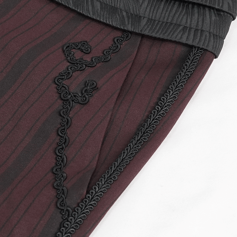 Close-up of elegant wine red gothic pants showcasing textured fabric and intricate black embroidery details.