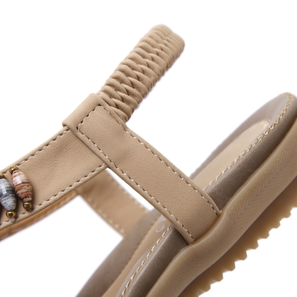 Close-up of ethnic style women's beaded sandals with elastic band and decorative stones.