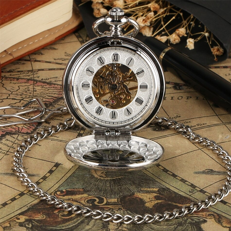 Antique mechanical pocket watch with intricate design and chain, resting on a vintage map with a notebook.