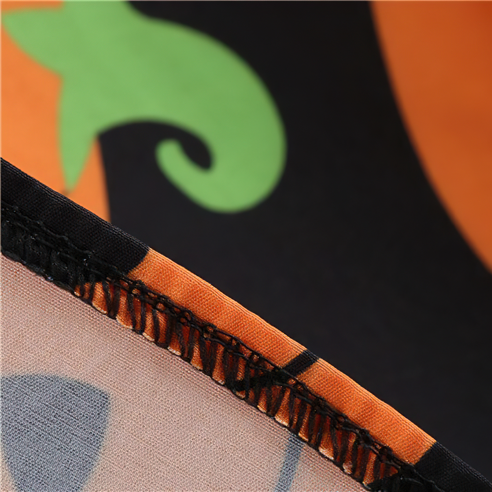 Close-up of pumpkin print detail and stitching on elegant women's Halloween dress.