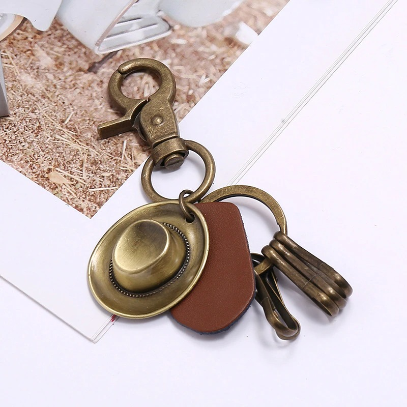 Vintage alloy hat keychain with brown leather pendant and bronze clip, perfect for car lovers.