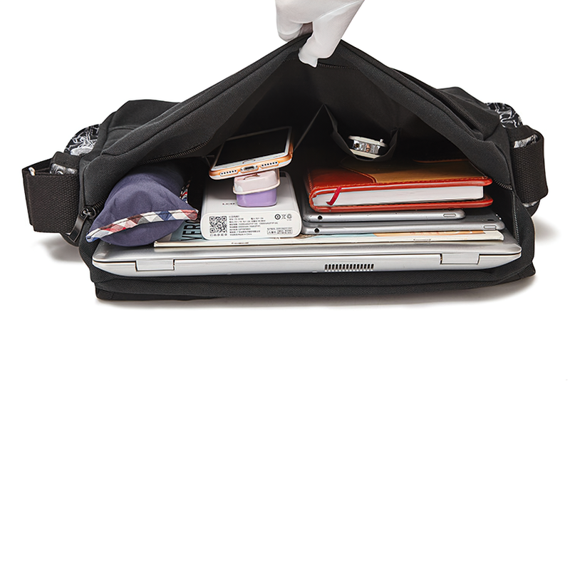 Inside view of a stylish black gothic shoulder bag filled with a laptop, notebooks, and personal items.