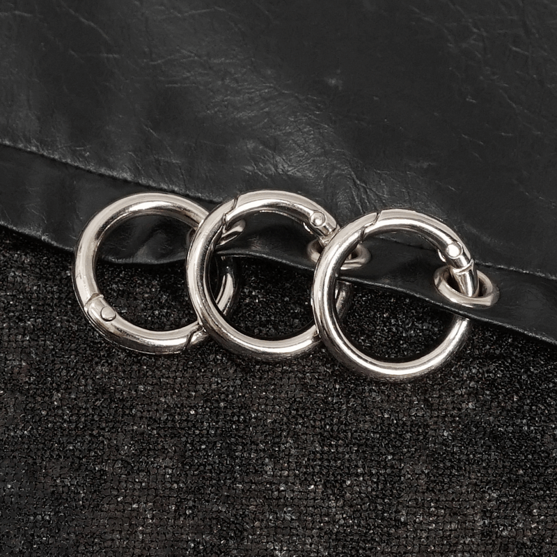 Three stylish metal rings on a black textured background, enhancing gothic fashion details.