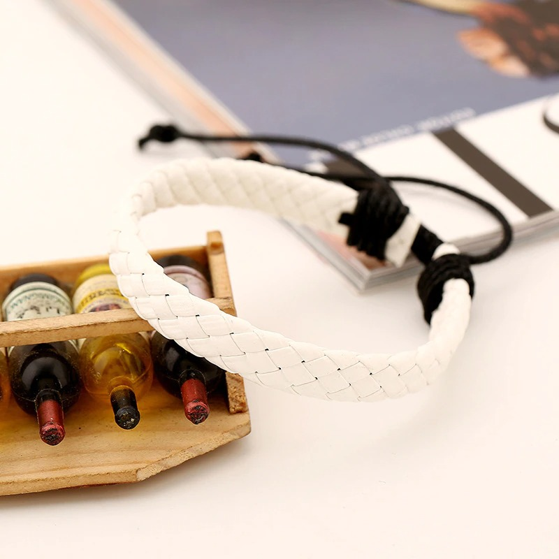 Handmade white braided leather bracelet on display with colorful vintage bottles, perfect for punk style fashion.