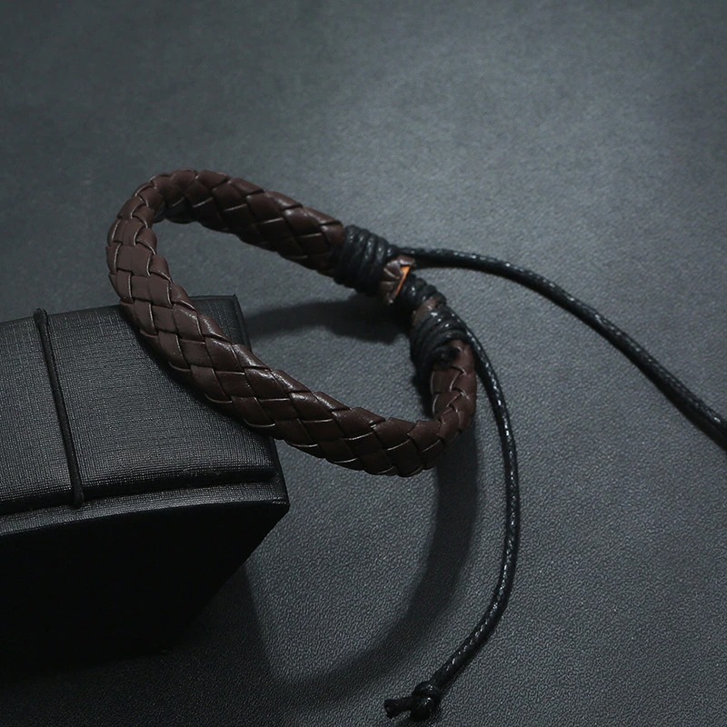 Handmade brown braided leather bracelet in punk style placed on a black box, perfect for unisex fashion.