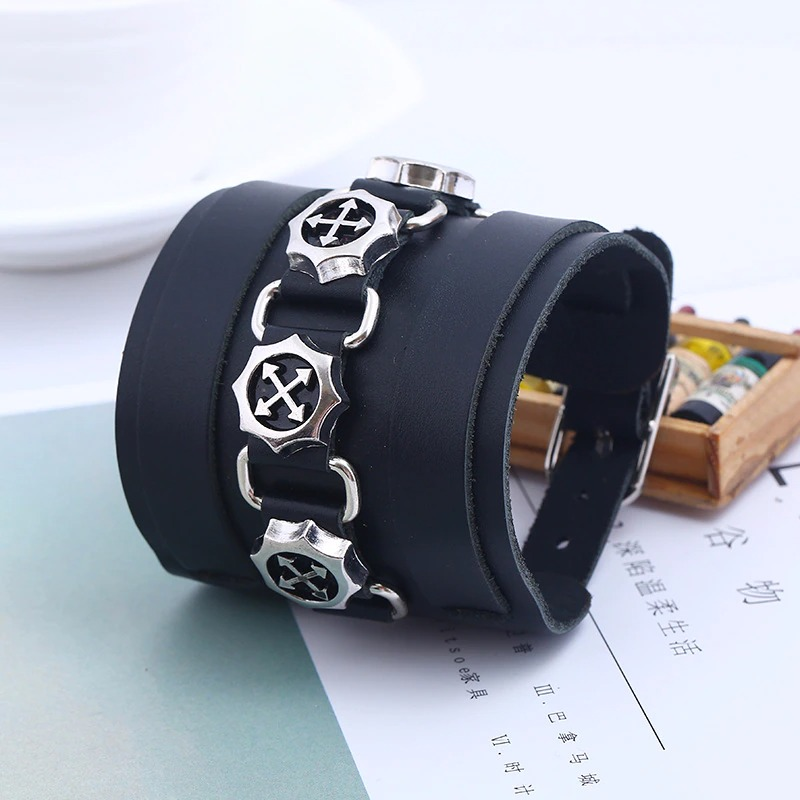 Wide black genuine leather bracelet with silver punk pendants on a stylish background.