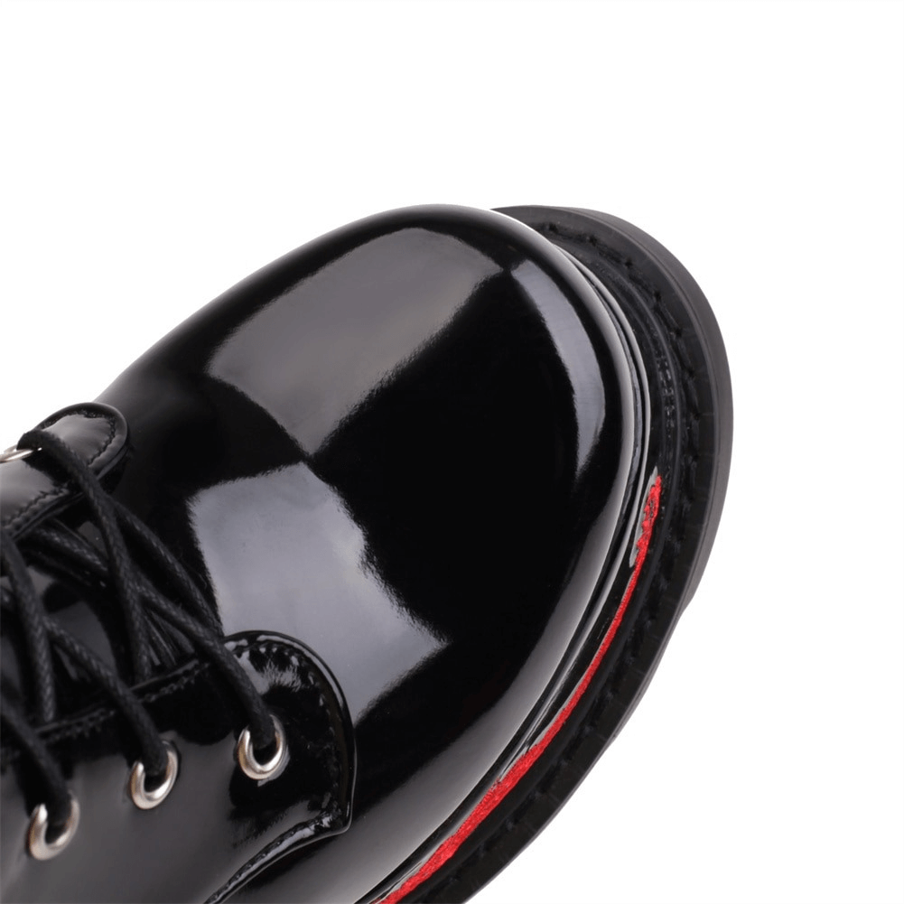 Close-up of stylish black patent leather shoe with laces, featuring a bold red sole for a fashionable look.
