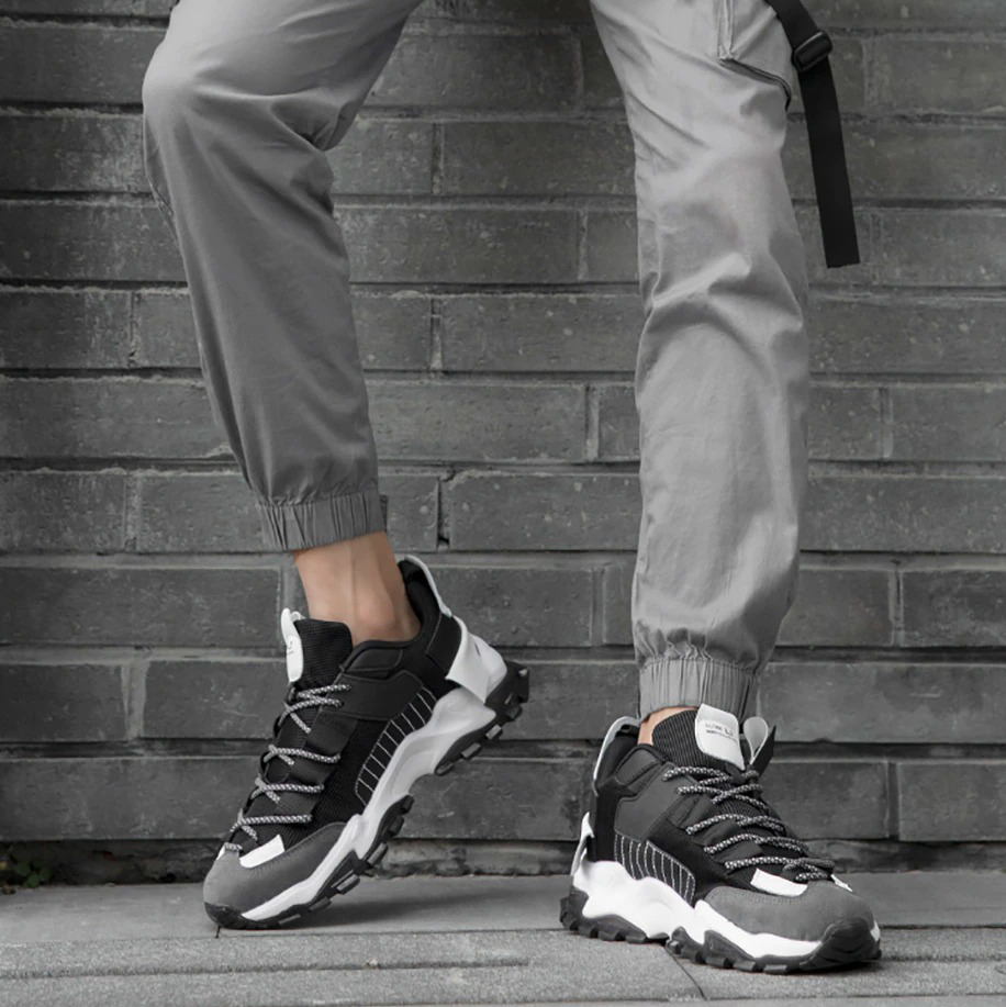 Stylish men's breathable sneakers in black and white, perfect for casual wear and running, paired with gray joggers.