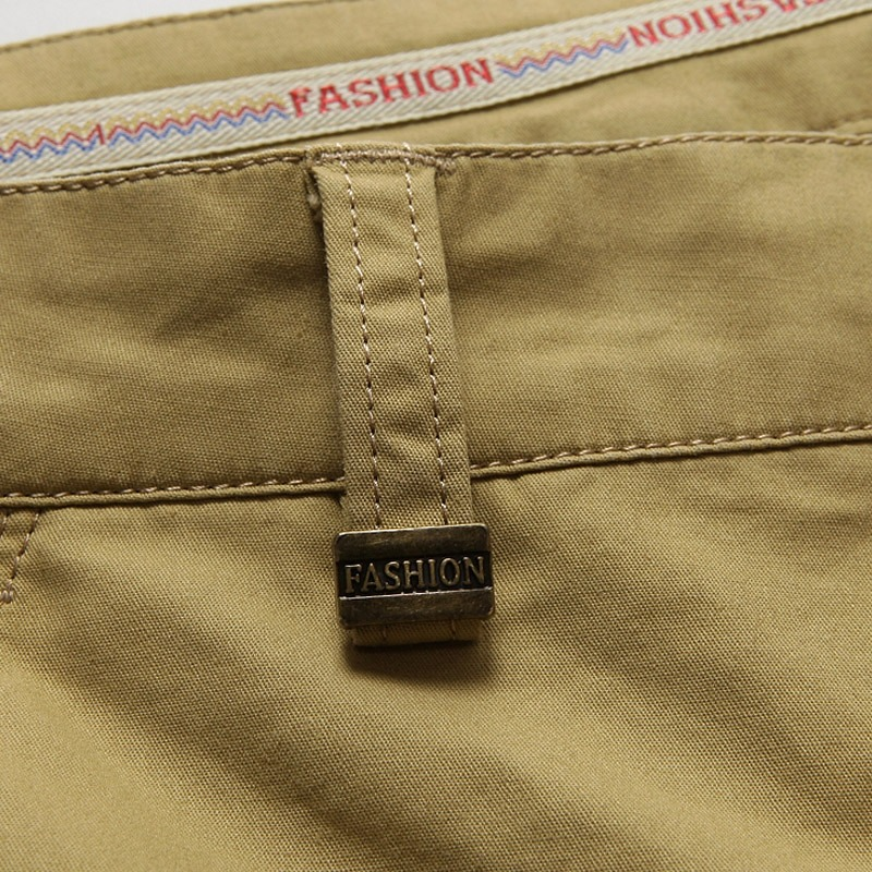 Detail of cotton men's cargo shorts waistband featuring a stylish 'FASHION' metal tag and contrasting label.