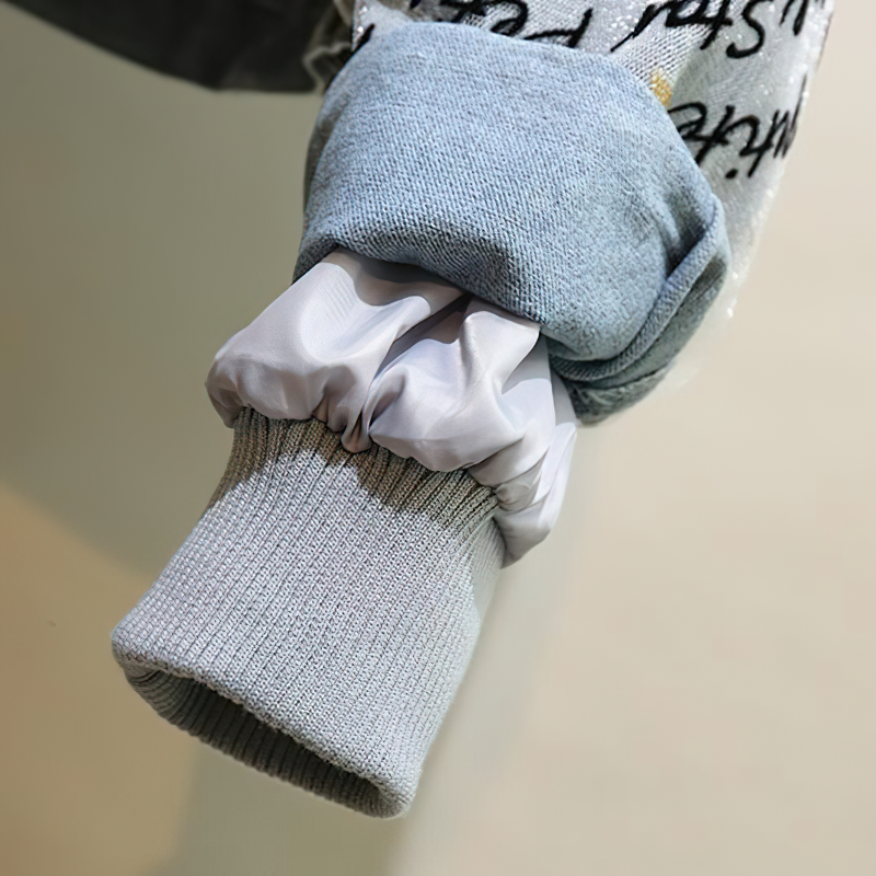 Close-up of fashionable denim parka sleeve with gray knit cuff and white lining, showcasing stylish embroidery details.