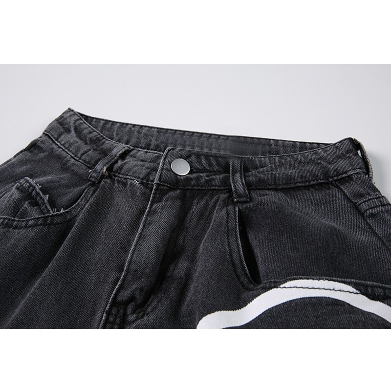 Close-up of the waistband and button of women's black jeans with ghosts print, showcasing casual style and denim texture.