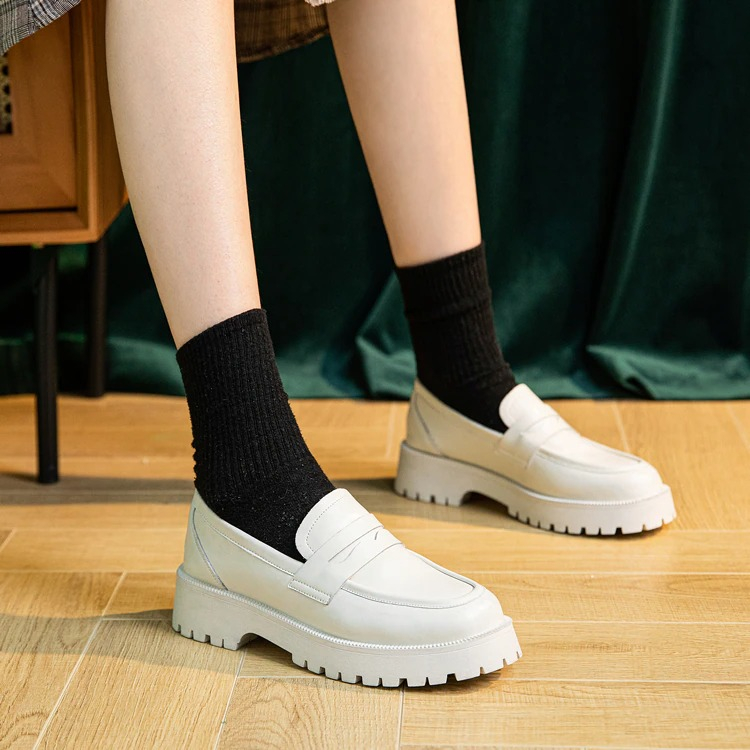 Stylish female white genuine leather loafers with thick soles, paired with black socks, perfect for casual spring outfits.
