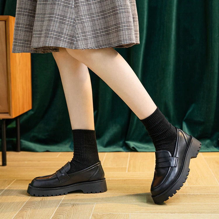 Trendy black genuine leather loafers styled with socks, perfect for casual spring fashion.
