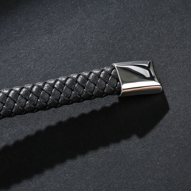 Close-up of a braided black leather bracelet with a shiny stainless steel clasp, perfect for gothic-style men's jewelry.