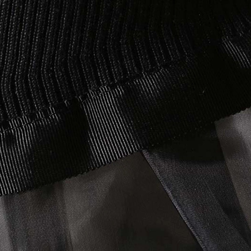 Close-up of the fabric detailing and layered design of a black gothic turtleneck sweater dress.