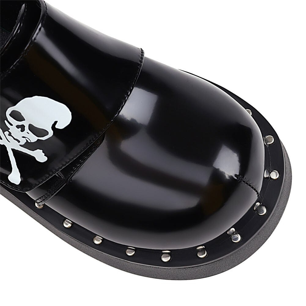 Close-up of gothic platform shoe with skull design and studded edges, showcasing premium patent leather style.
