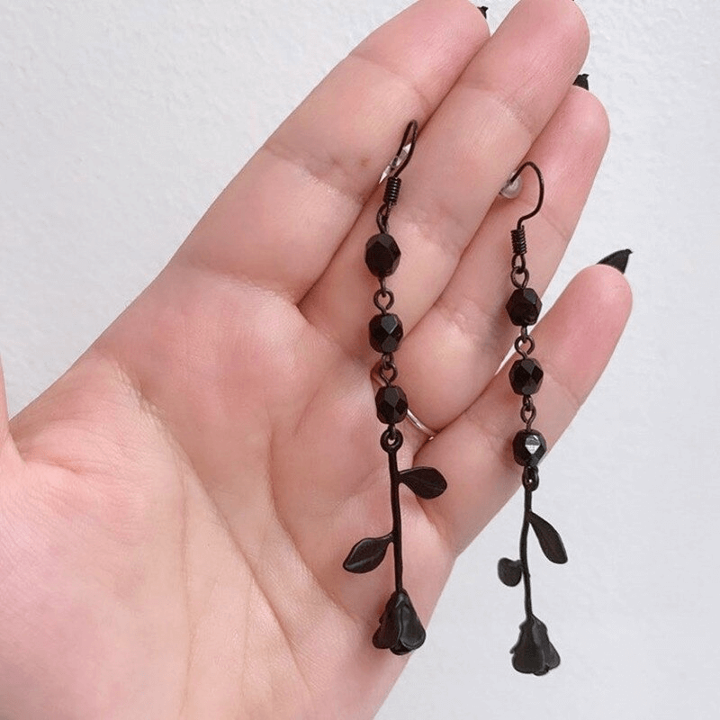 Gothic black rose beaded earrings showcased on a hand, featuring elegant floral design and sparkling beads.