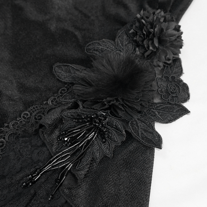 Close-up of black velvet fabric adorned with intricate lace and floral accents for gothic fashion.