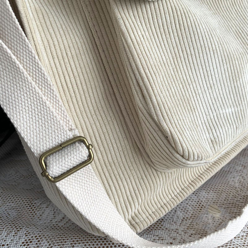 Close-up of a cream corduroy handbag with a stylish strap, showcasing its luxurious texture and quality craftsmanship.