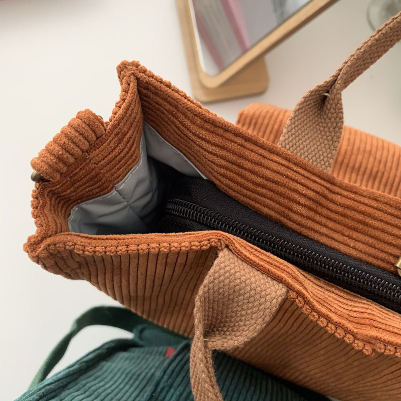 Interior view of a stylish corduroy handbag showcasing its luxurious fabric and zippered compartment.
