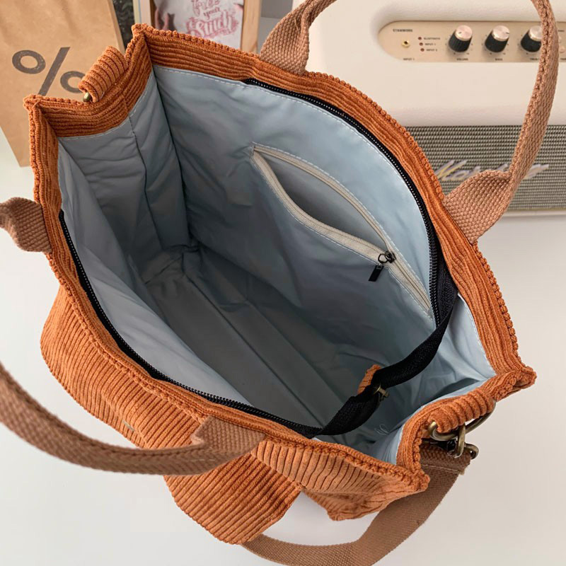 Inside view of a stylish ladies corduroy handbag showing spacious compartments and a zipper pocket.