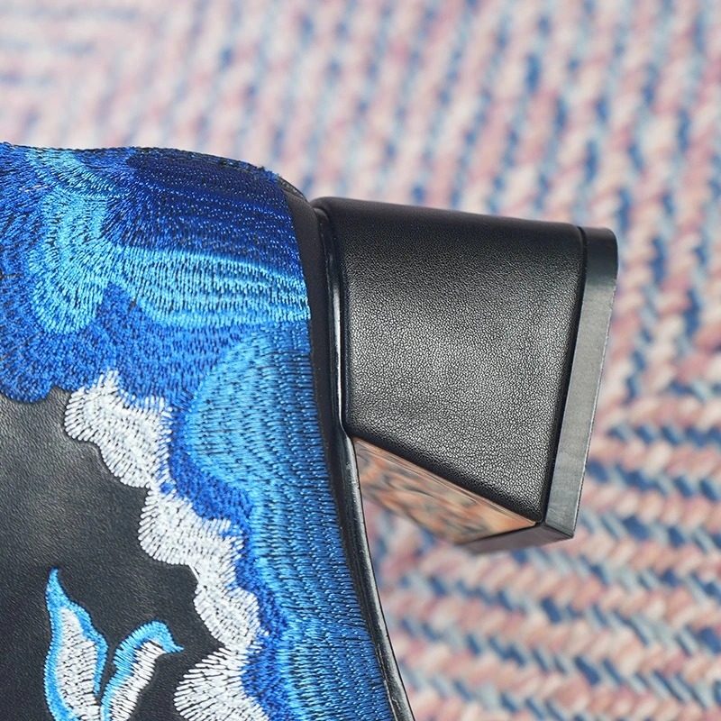 Close-up of casual square heel of ladies genuine leather ankle boots with ethnic embroidery detail.