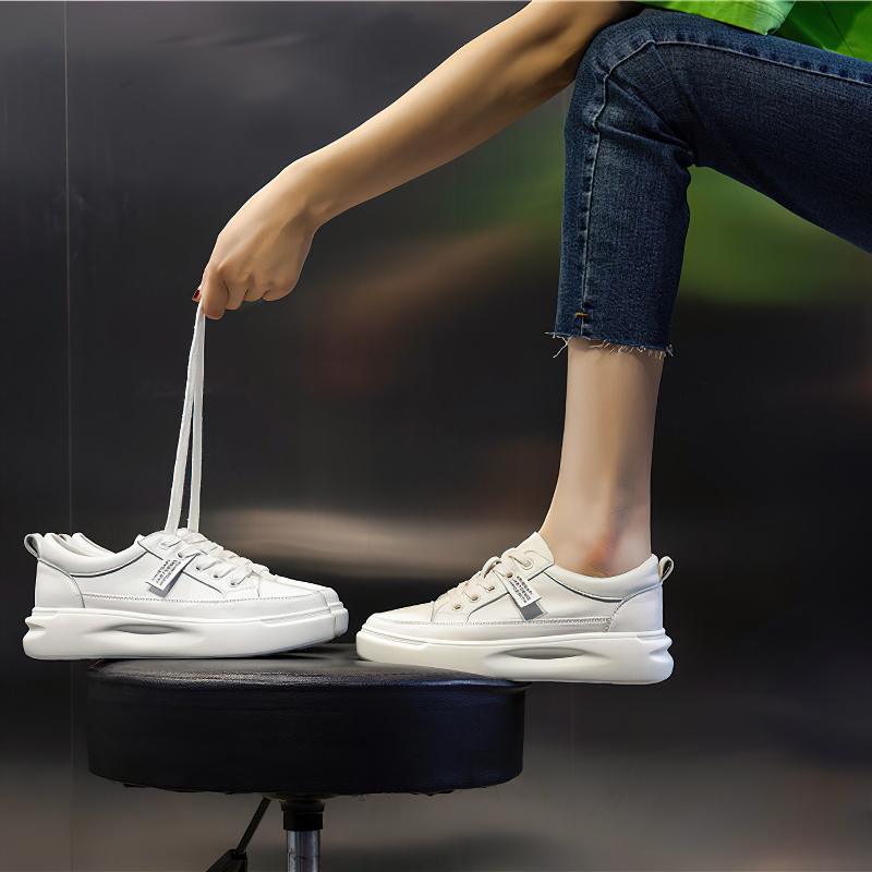 Fashion ladies lace-up genuine leather sneakers in white, showcased with a hand holding the shoelaces, perfect for casual wear.