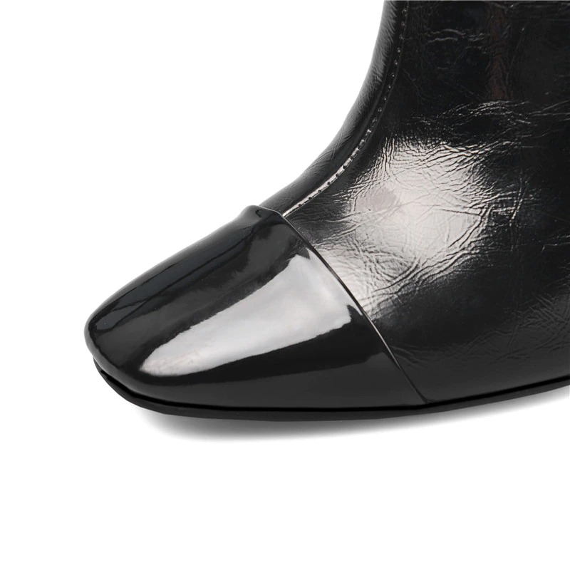 Close-up of stylish black mid-calf boot with glossy pointed toe and textured leather finish.