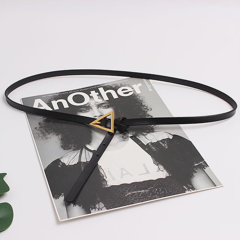 Trendy black PU leather belt with metal triangle buckle on a fashion magazine backdrop.