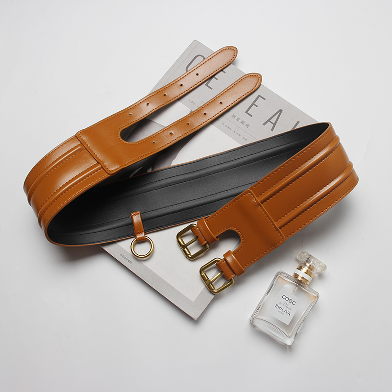 Fashion ladies wide PU leather corset belt in brown with double buckle, displayed with a perfume and magazine for styling inspiration.