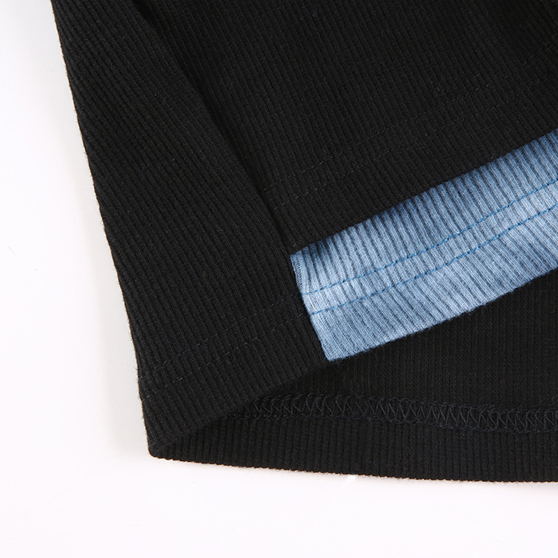 Patchwork detail of women's gothic black crop top featuring blue fabric accents.