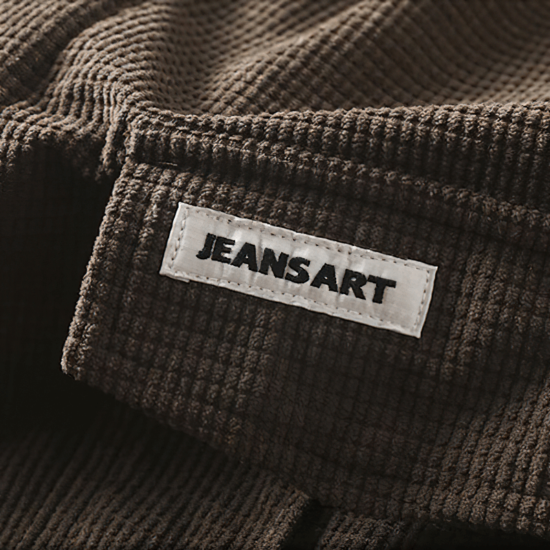 Close-up of JEANSART label on textured brown fabric, showcasing quality and style in casual wear.