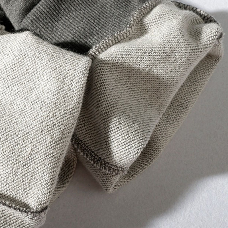 Close-up of elastic waistband and stitching detail on casual men's loose pants in gray and cream colors.