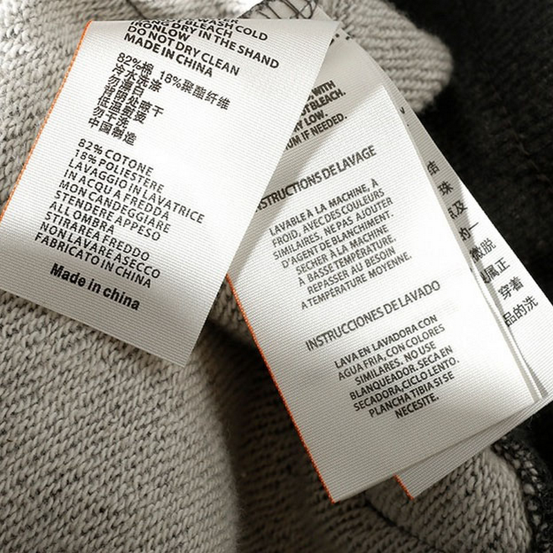 Clothing care labels showing fabric composition and washing instructions for casual pants.