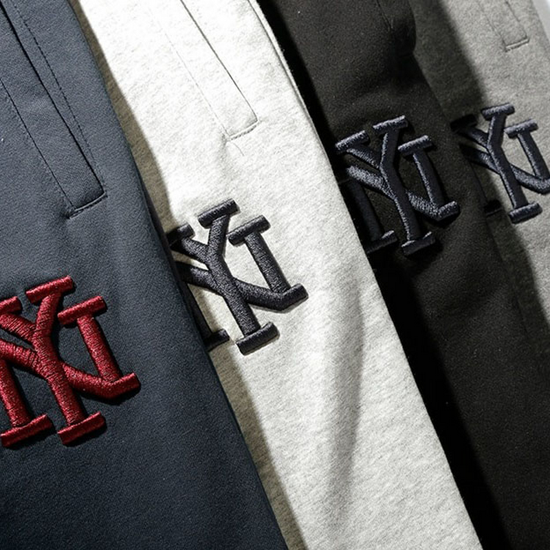 Fashion Male Elastic Waist Drawstring Loose Pants in navy, grey, black, and maroon with logo detail.