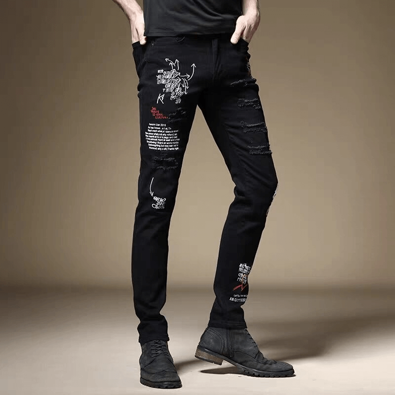 Stylish male model wearing black slim jeans with letter prints and distressed details, showcasing casual fashion.