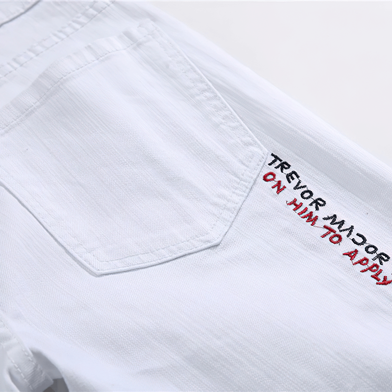 Close-up of white jeans featuring stylish embroidered text on the pocket, perfect for casual outfits with a modern twist.