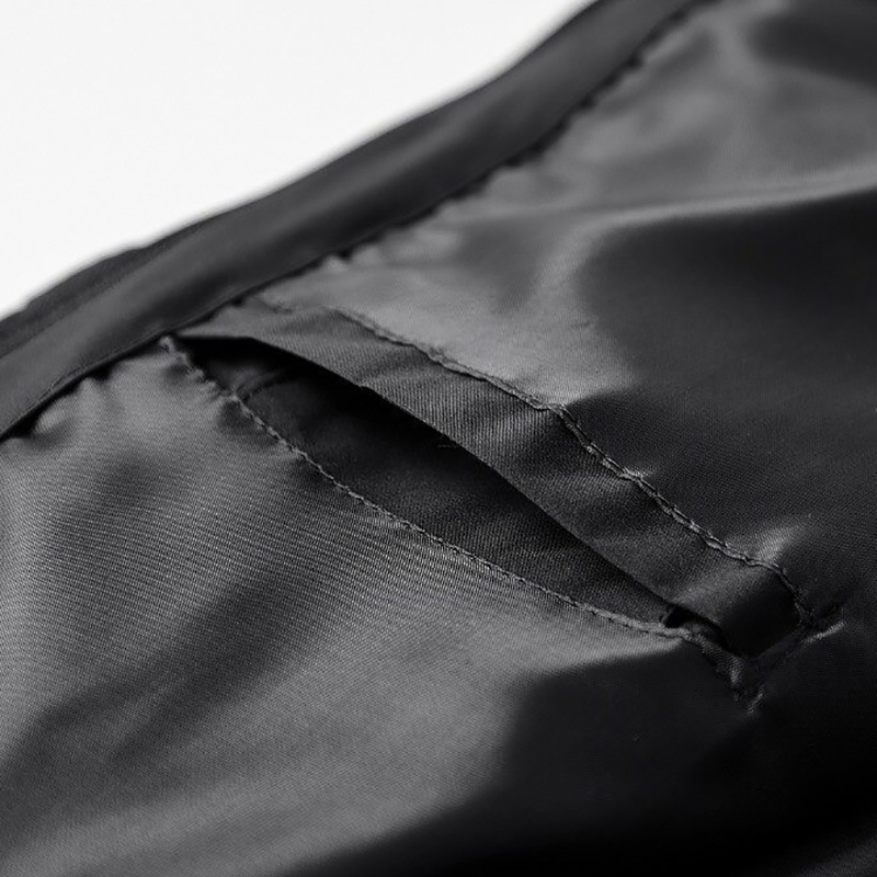 Close-up of the smooth inner lining and pocket detail of a men's black zip-up jacket with hoodie.