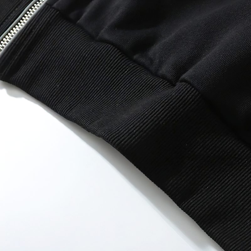 Close-up of the ribbed hem and zipper detail on a stylish black oversized men's hoodie.