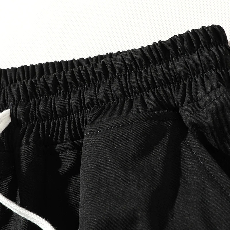 Close-up of men's elastic waist shorts in black, showcasing a comfortable waistband and drawstring for casual wear.