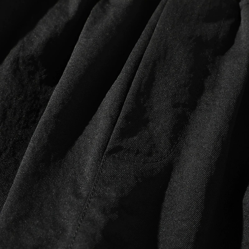 Close-up of black fabric showing texture and details of men's elastic waist shorts for casual wear.