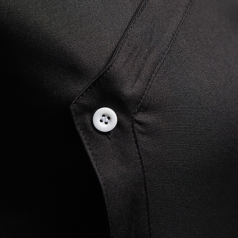 Close-up of a black men's embroidered asymmetric shirt featuring a white button detail.