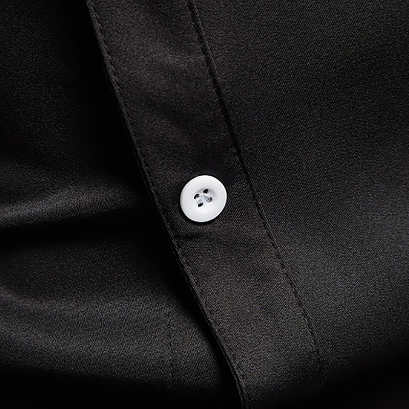 Close-up of button detail on a black men's asymmetric long-sleeved shirt with smooth fabric.